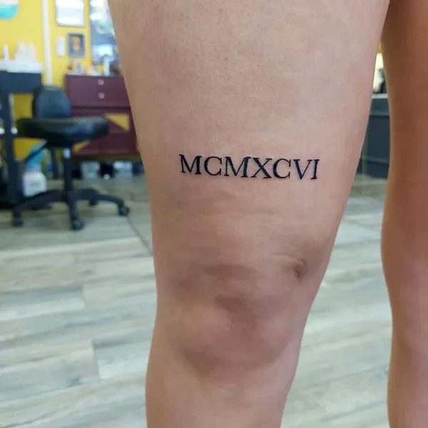 Roman numerals above knee tattoo