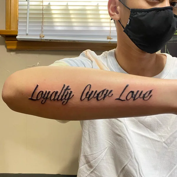 Loyalty over love tattoo on forearm